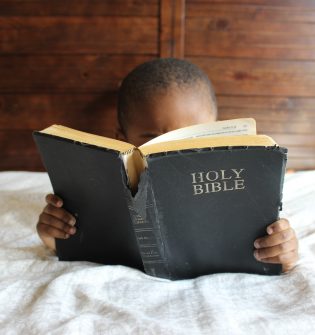 A child reading the bible on his bed