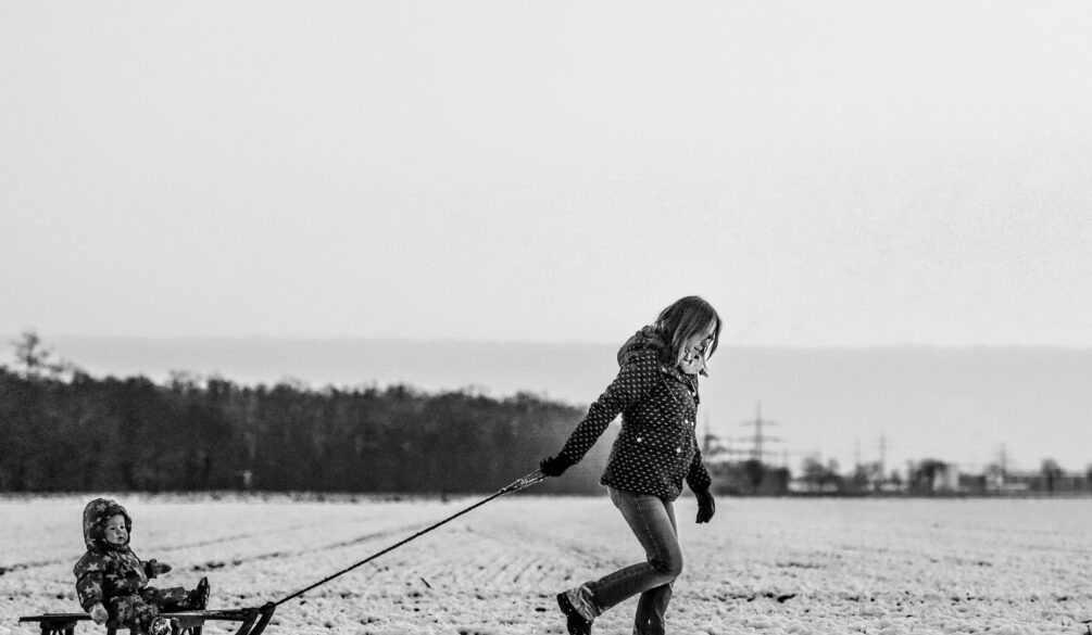A woman walking in the snow with two skis.